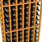 Close-up of honey-toned 6-column wine bottle rack with bottle necks visible