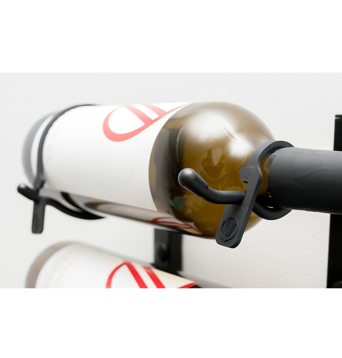 Wall-mounted bottle retention strap, black clamp holding a bottle in place
