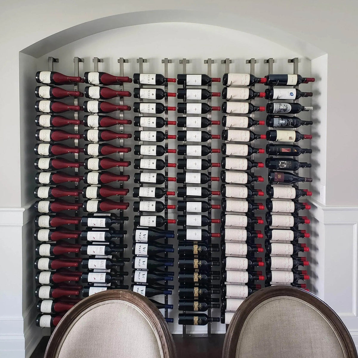 Wall standoff bracket, not clearly visible; wall of wine bottles fills the frame
