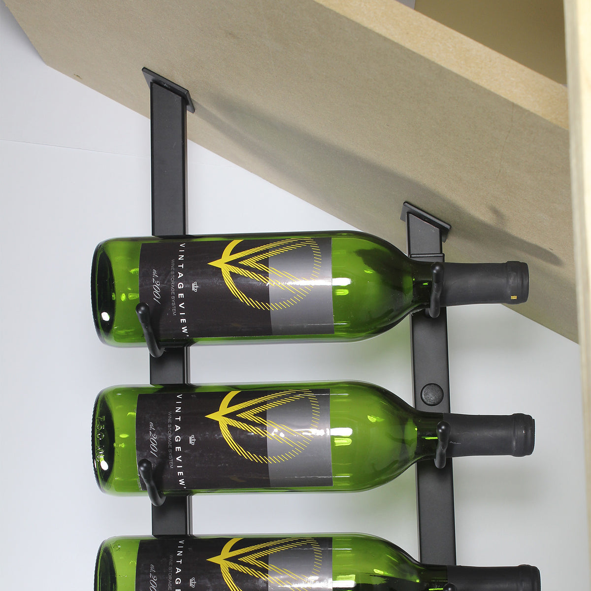 Metal wall-mounted angled base plate with three holders holding green wine bottles