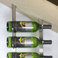 Wall-mounted angled base plate with three bottle holders holding green wine bottles