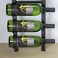 Wall wine bottle display with green bottles in a black metal frame and hidden base mounts