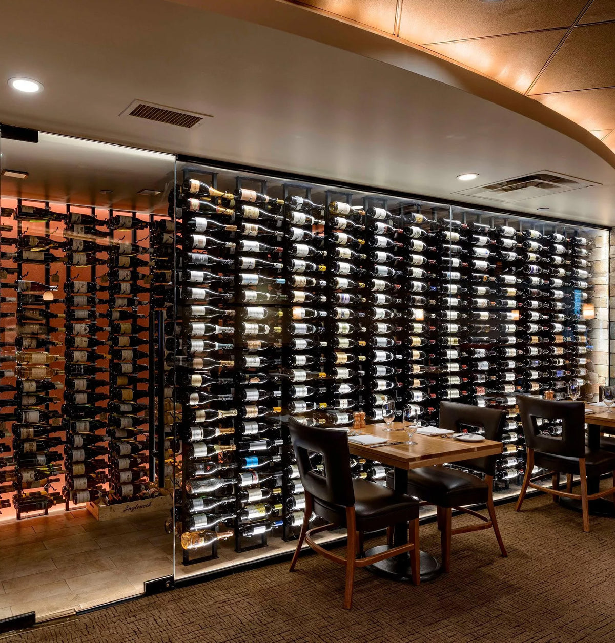 Double-sided wall wine rack with multiple rows of filled wine bottles behind panels