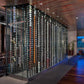 Double-sided wall wine rack with rows of filled wine bottles behind glass panels