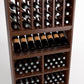 Close-up of wood wine rack with arched bottle slots, angled rows, and cubby bins