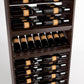 Close-up of wine bottle display rack with dark wood shelves holding bottles in bottle rails and rows