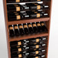 Close-up view of dark wood wine bottle rack showing bottles in rails above and in row holders below