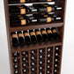 Brown wood wine rack with top horizontal bottle rails, middle wine shelf, and lower bottle cubbies