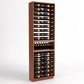 Tall freestanding wooden wine bottle rack with horizontal bottle slots and curved base.