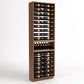 Tall wooden wine bottle rack with many horizontal slots and a curved bottom section.