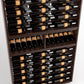 Close-up of wine bottle rack shelves holding bottles with orange labels in dark wood