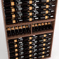 Close-up view of wine bottles resting in black bottle slots within a wood cabinet