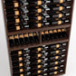 Close-up of wine bottles on rails above a lower cradle row in a wood wine cabinet
