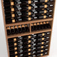 Wine bottle rack showing rows of black bottles with orange labels on wood shelving