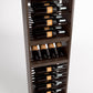 Close angled view of wooden wine rack with rows of bottles on horizontal rails