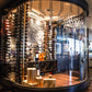 Wall-mounted wine bottle rack in a circular glass display with rows of bottles