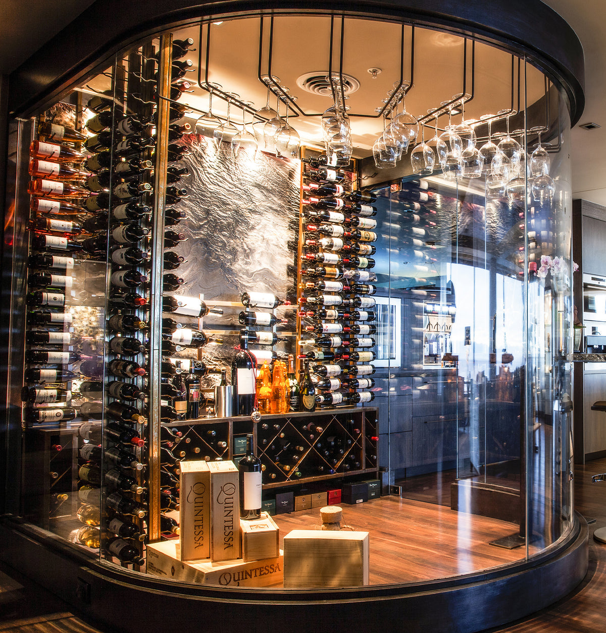 Wall-mounted wine bottle rack in a circular glass display with rows of bottles