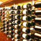 Wall-mounted wine bottle rack with metal uprights holding rows of wine bottles