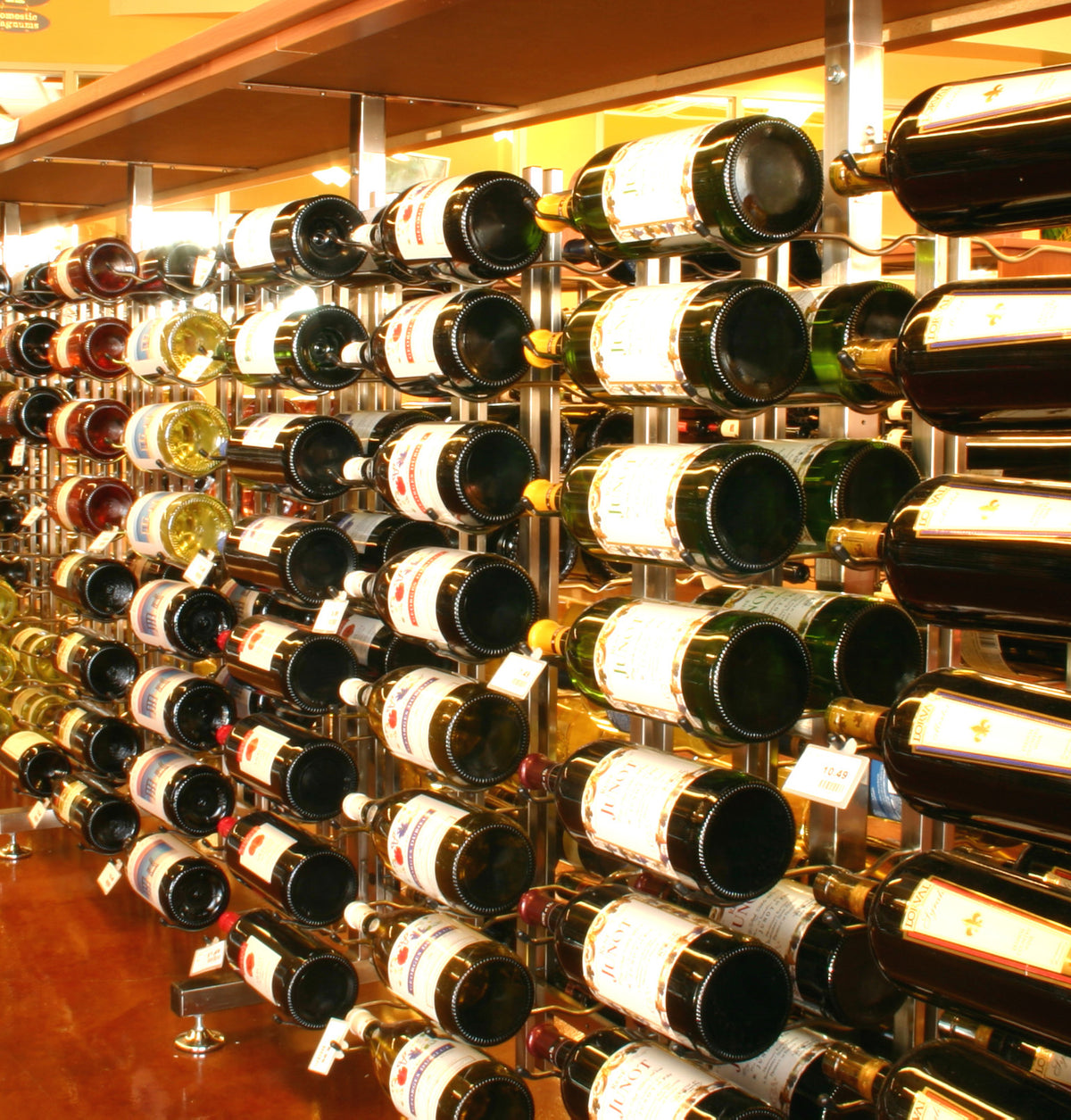 Wall-mounted wine bottle rack with metal uprights holding rows of wine bottles