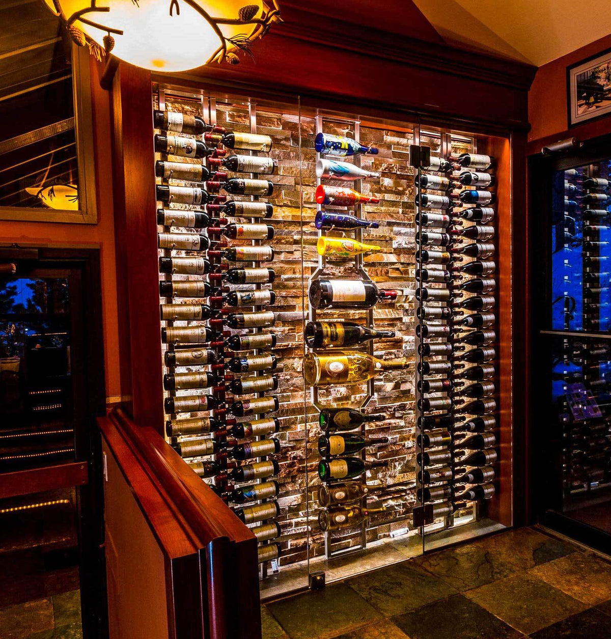 Wall-mounted wine bottle rack with bottles displayed in a clear wall panel