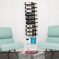 Black wall wine bottle rack holding mixed wine bottles on metal pegs