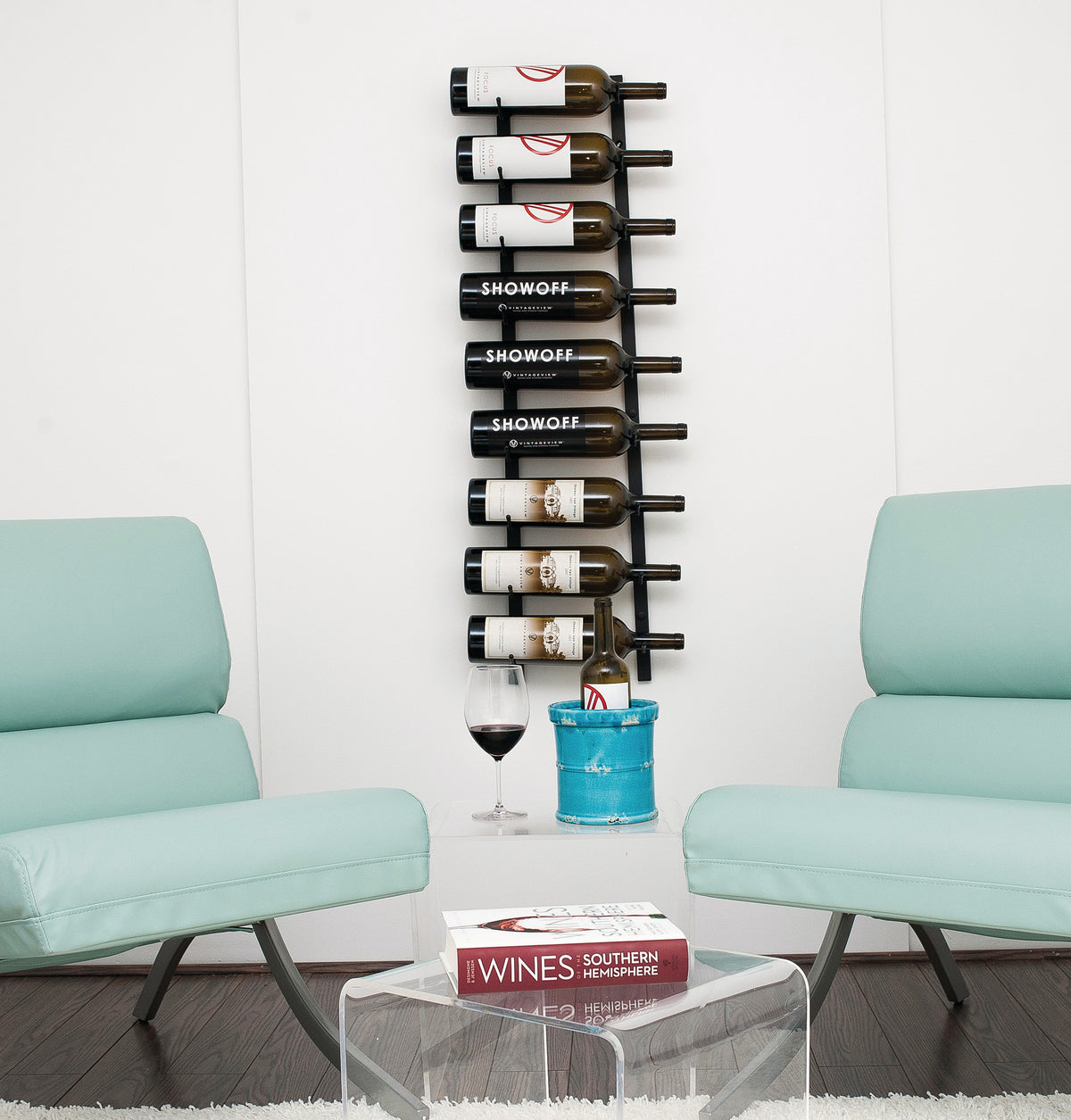 Black wall wine bottle rack holding mixed wine bottles on metal pegs