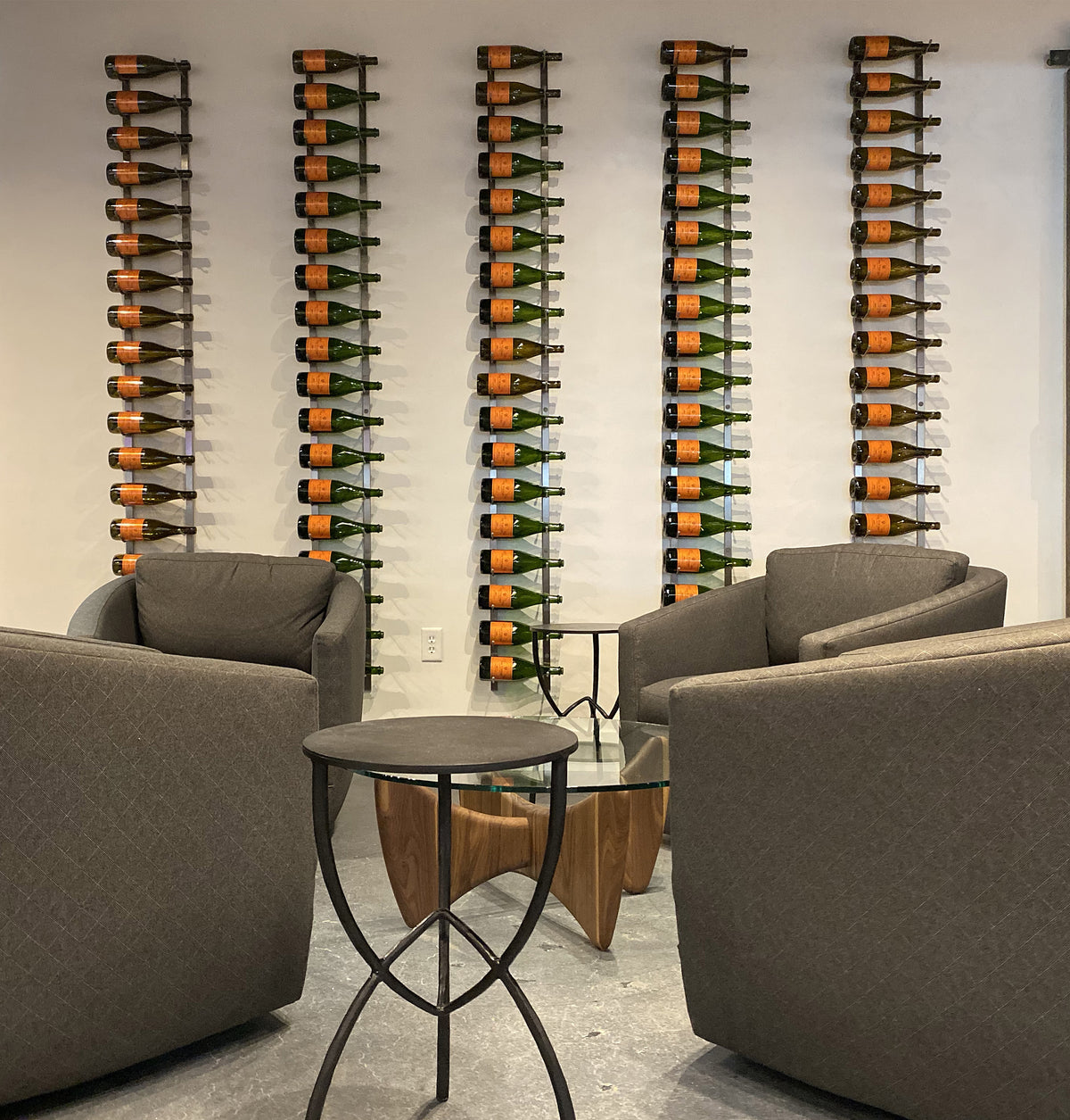 Wall-mounted wine bottle rack with curved hooks holding multiple bottles; metal frame