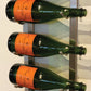 Wine bottle rack detail with green bottles and orange labels on vertical metal bars