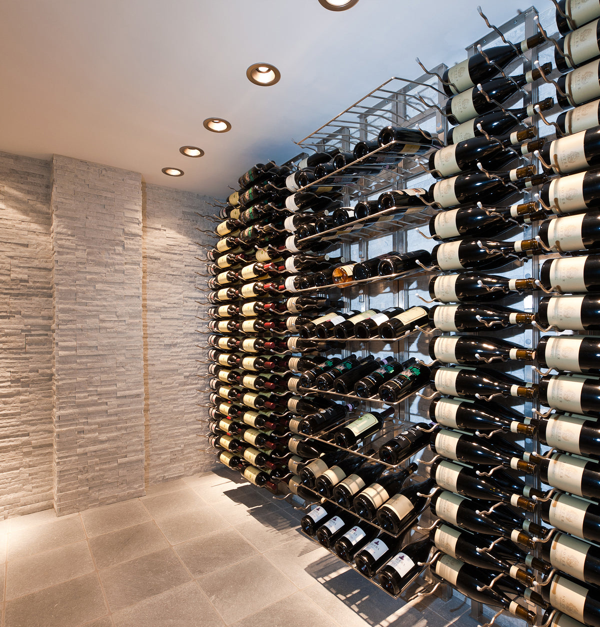 Corner wine bottle wall display with tightly arranged bottles and metal back supports