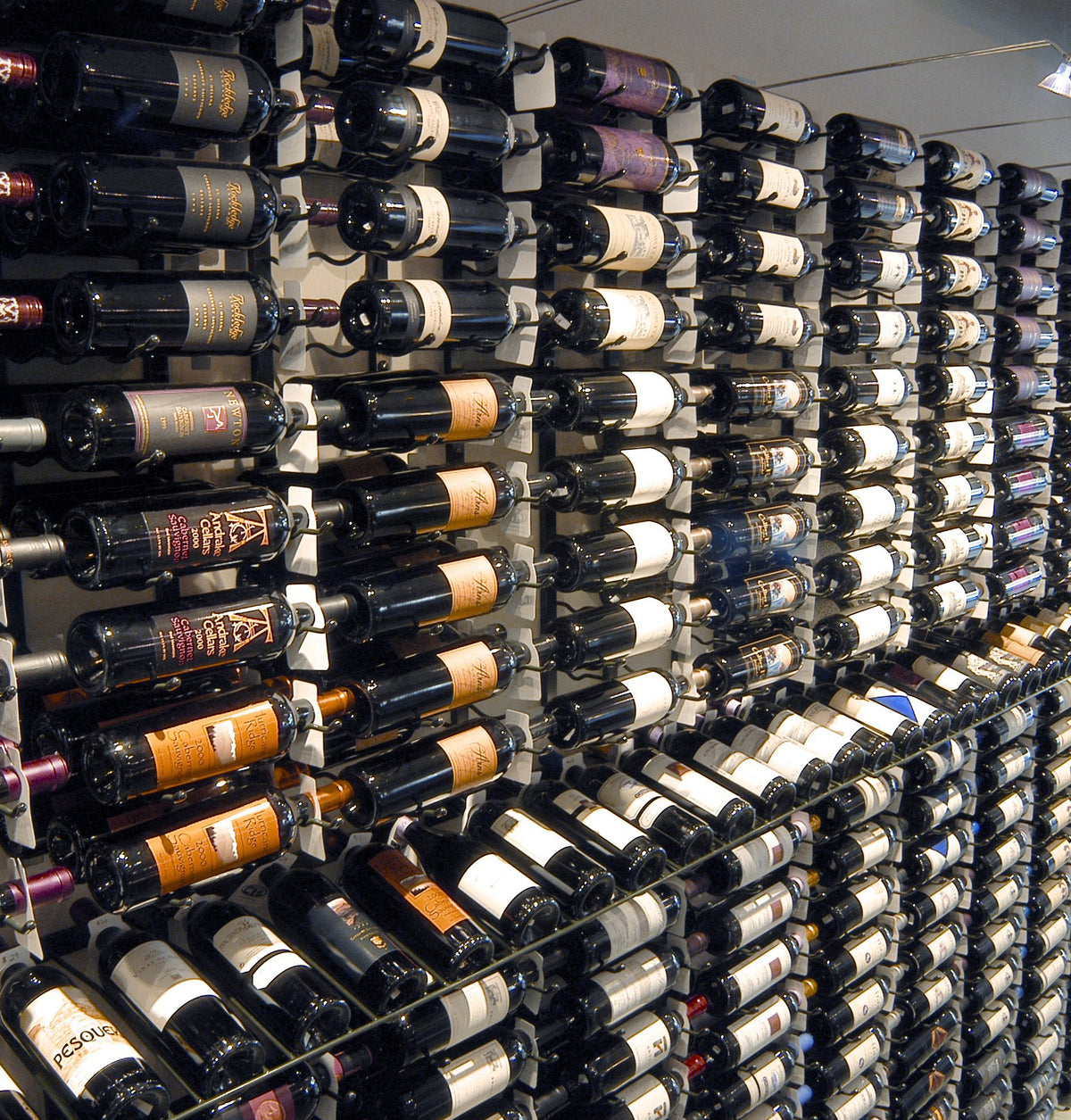 Wall-mounted wine bottle display with multiple black bottles in a grid rack