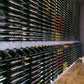 Large wall of wine bottles arranged in grid rows with label bands on dark bottles