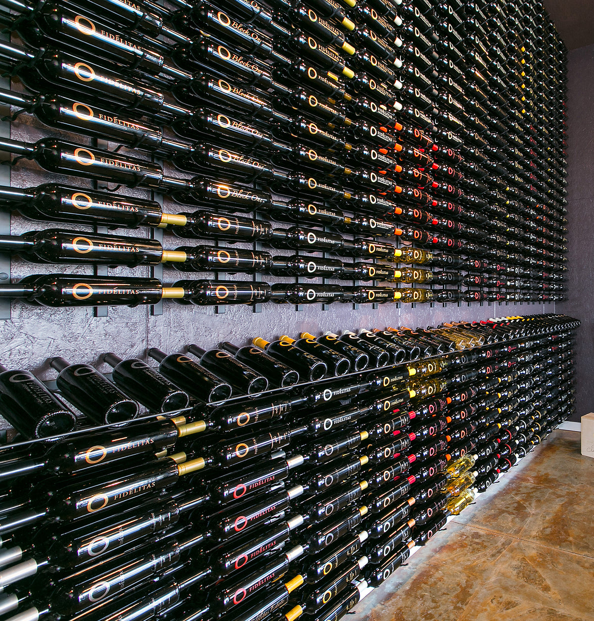 Large wall of wine bottles arranged in grid rows with label bands on dark bottles