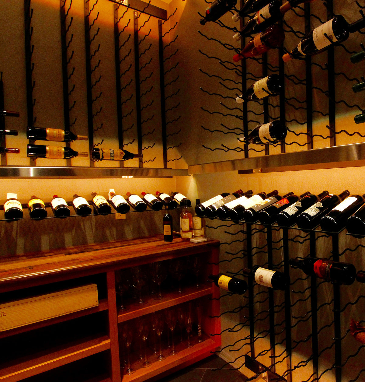 Wine bottle wall rack with rows of bottles in dark holders and countertop display