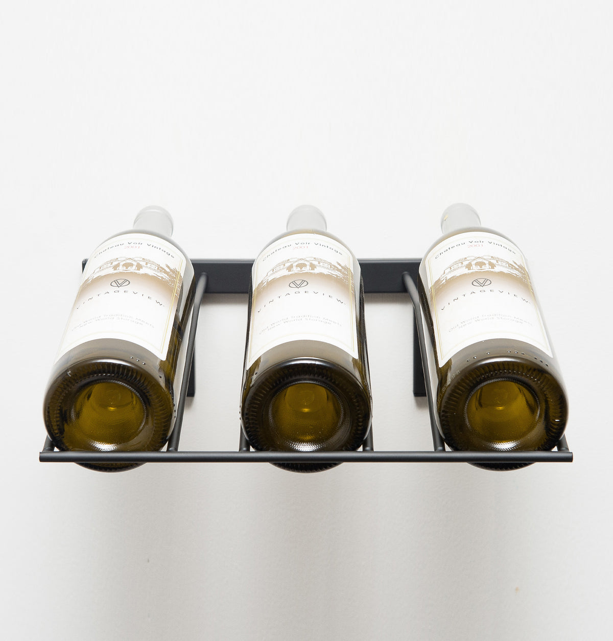 Wall-mounted wine bottle rack holding three bottles with white caps, front view.