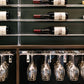 Wood bar display with hanging stemware under a wall-mounted rack