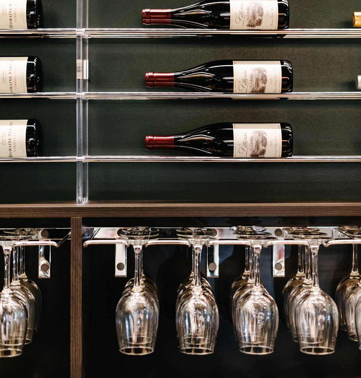 Wood bar display with hanging stemware under a wall-mounted rack
