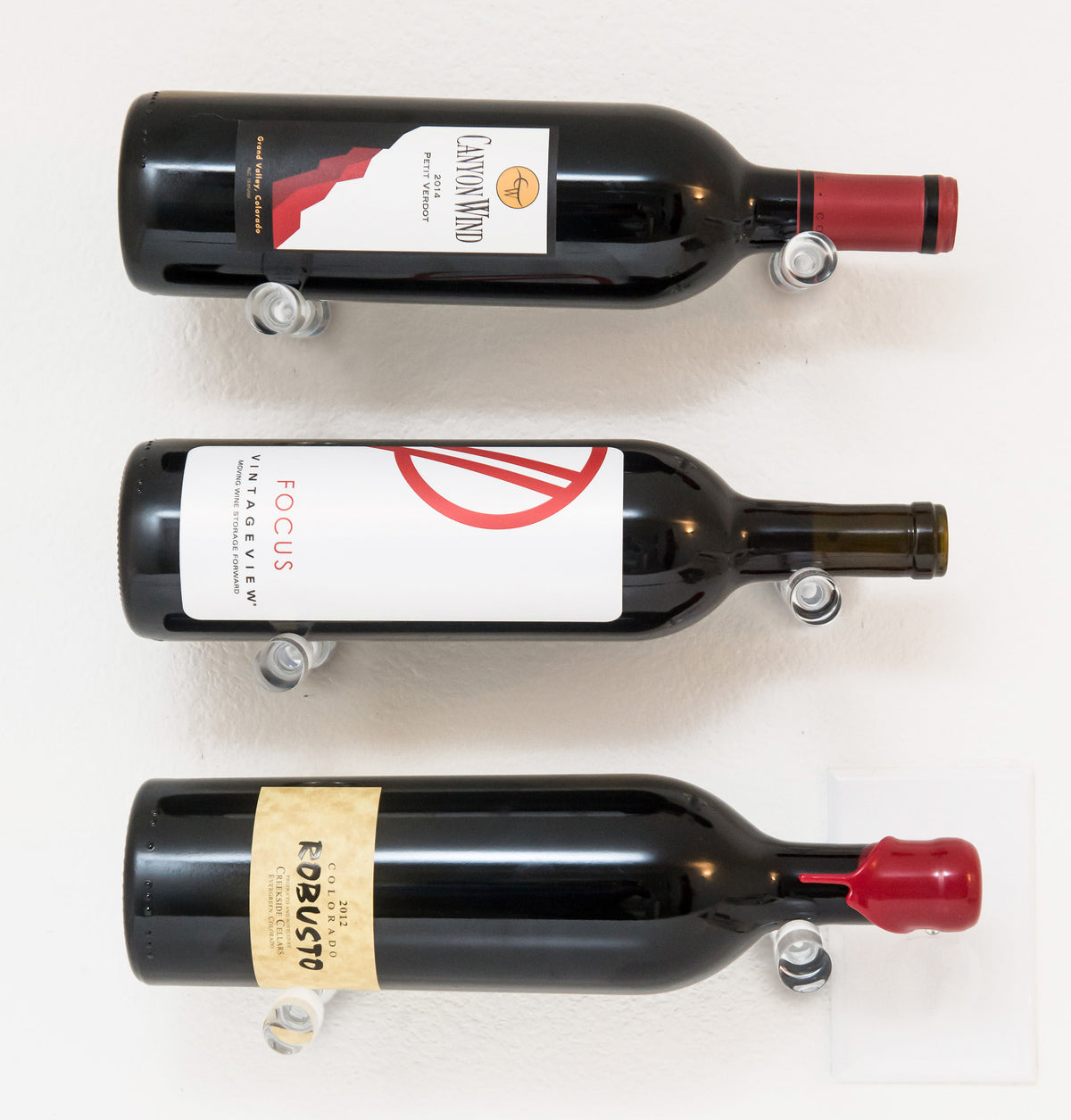 Set of wall-mounted wine bottle pins with metal bases holding three bottles