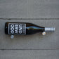 Wine bottle holder pins with silver prongs securing a dark wine bottle on tile