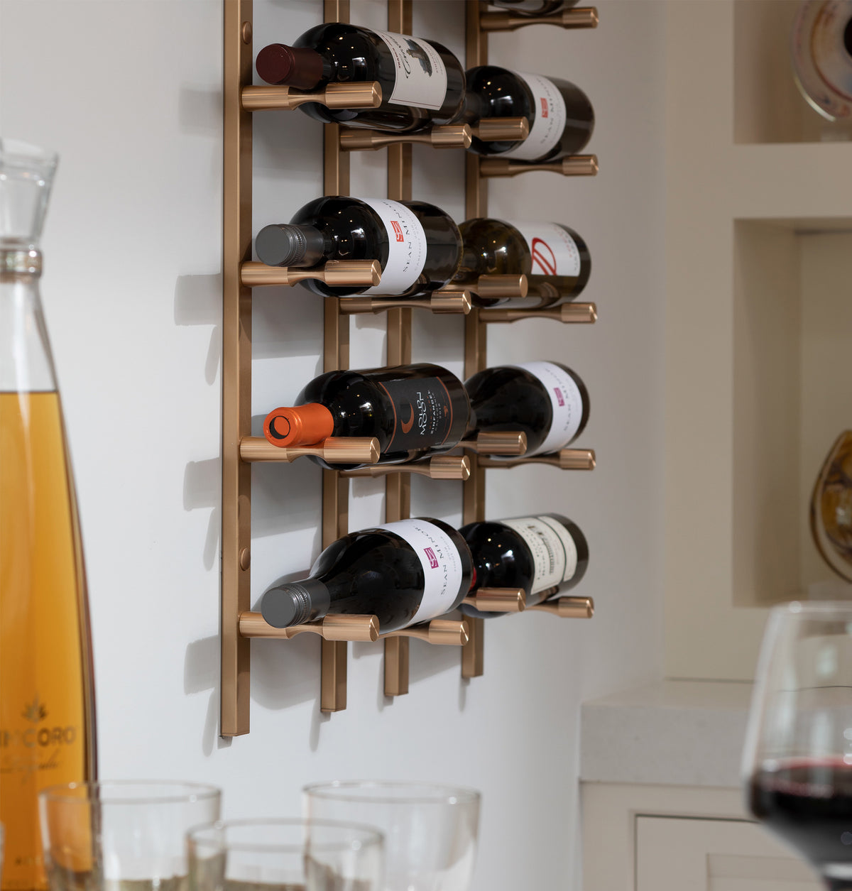 Wall-mounted wine bottle rack with bottles stored on golden bronze slots