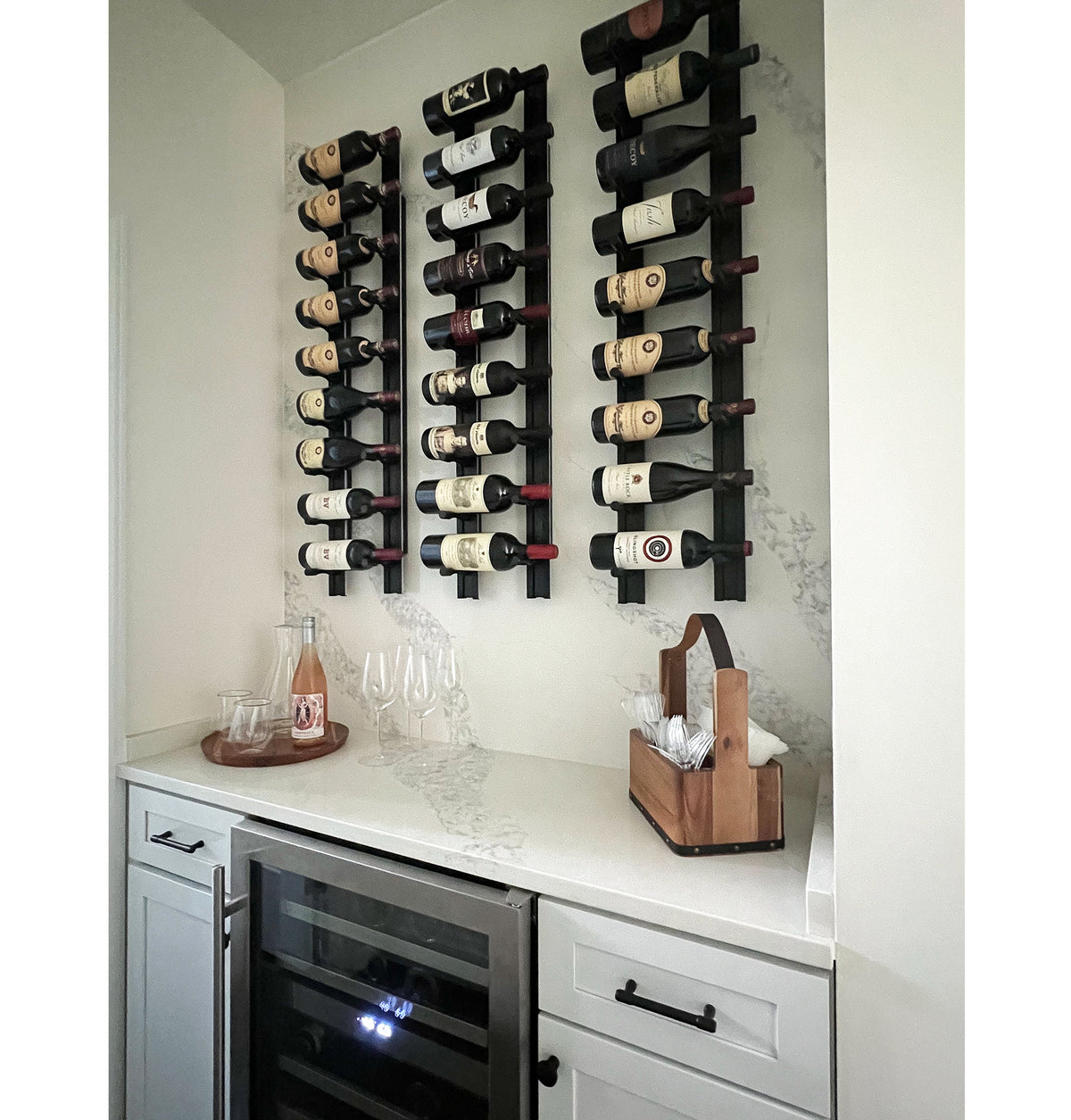 Wine bottle pin rack on wall with multiple bottles on black rails