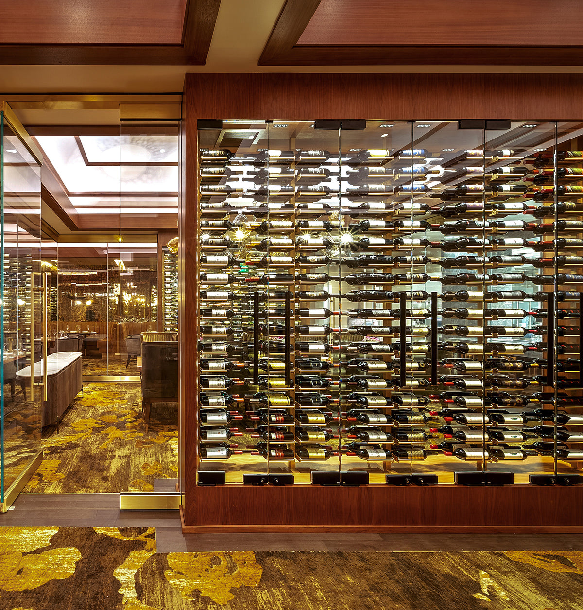 Double-sided wine rail system with many bottle slots in a wood-paneled display area