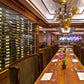 Double-sided bottle display rails along a long bar, with bottle rows on glass panels