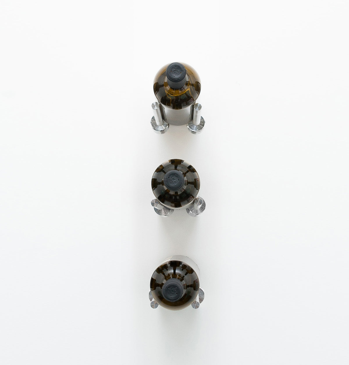 Wall-mounted 3-bottle rail with three clear bottle-holder caps and a dark metal base