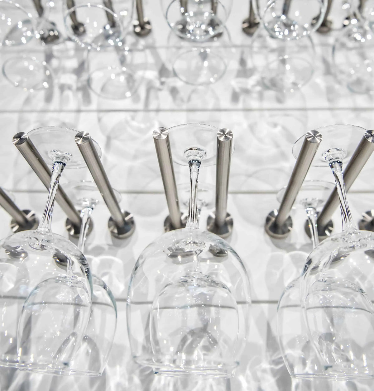 Set of stemware goblets on two-bar stemware rack with polished metal holders