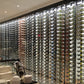 Wall-mounted wine rack wall with many metal bottle slots and wine bottles