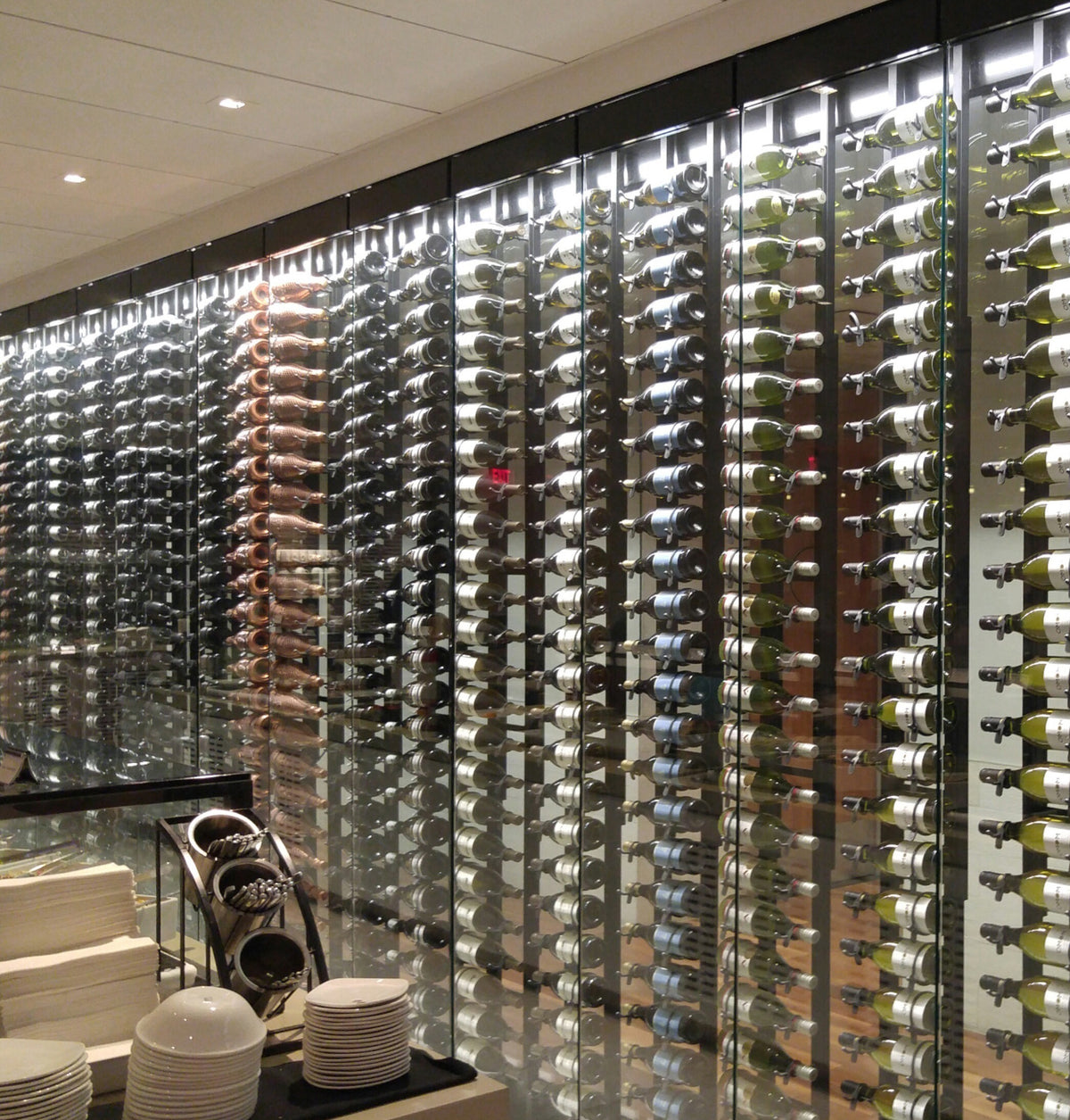 Wall-mounted wine rack wall with many metal bottle slots and wine bottles