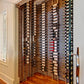 Indoor wall wine rack display with multiple rows of wine bottles and black holders