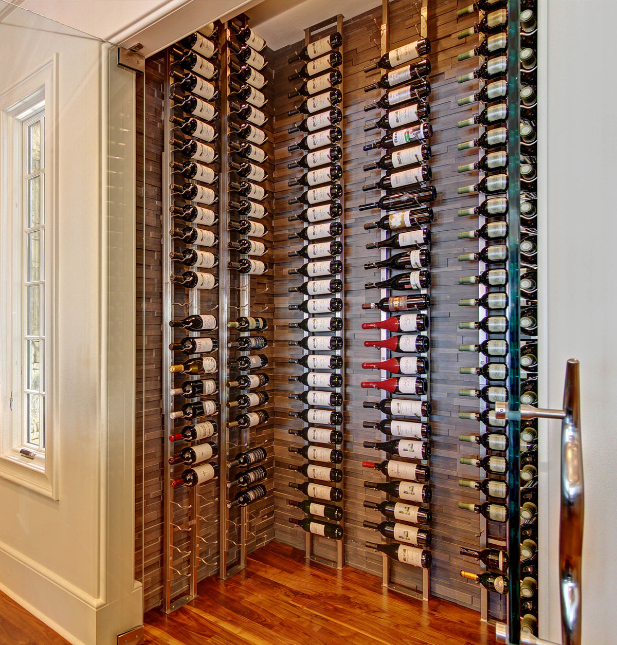 Indoor wall wine rack display with multiple rows of wine bottles and black holders