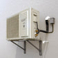 Wall-mounted split-system condenser unit, cream/white with open service cover and pipes