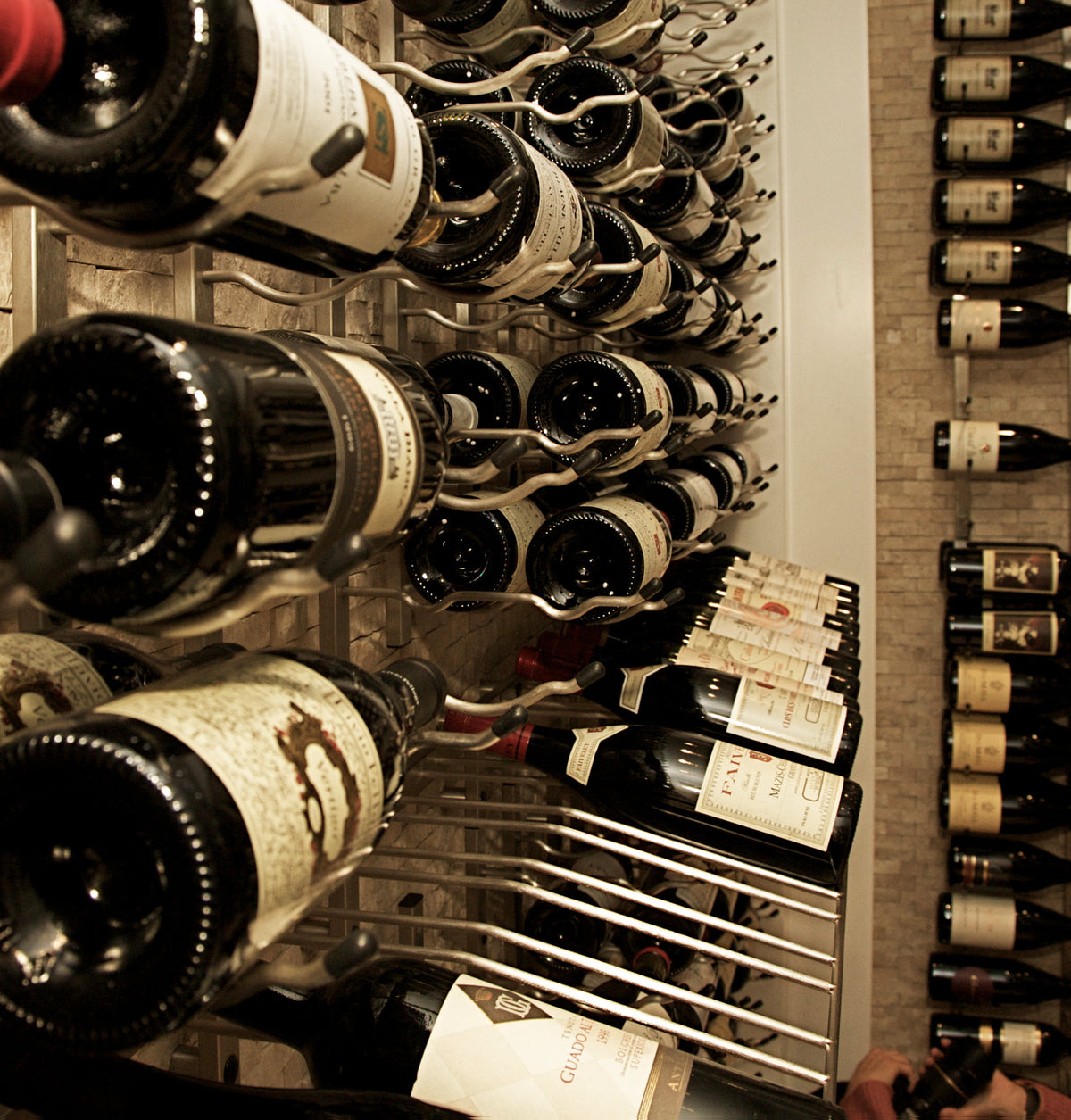 Close-up of bottle necks in metal holders along the wine rack